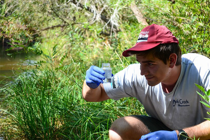 Volunteer taking a water sample from Oak Creek